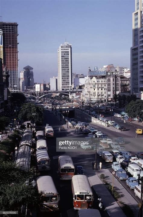 Buses And Cars Are Parked On The Street In Front Of Tall Buildings