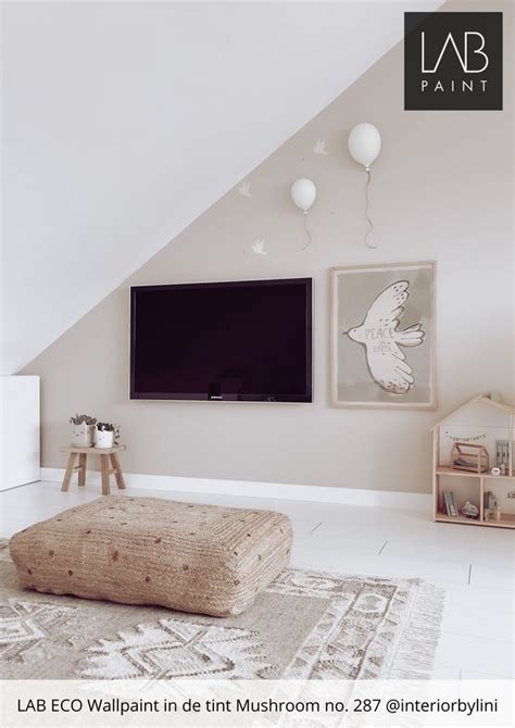 A Living Room With White Walls And An Ottoman In Front Of A Tv Mounted