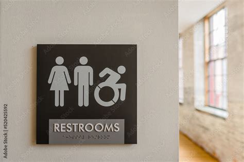 Close-up of unisex bathroom sign against neutral colored wall with ...