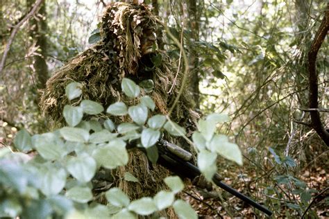 A Marine sniper wearing sniper camouflage gear known as a "ghillie ...