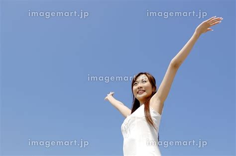 青空の下で両手を広げる女性の写真素材 [23973314] イメージマート