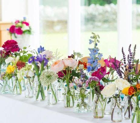 There Are Many Vases With Flowers In Them On The Table Next To Each Other