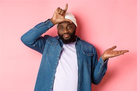 Sad African American Man Showing Loser Sign On Forehead And Staring At Camera Standing Over