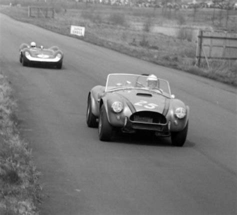 Two Race Cars Driving Down The Road In Black And White