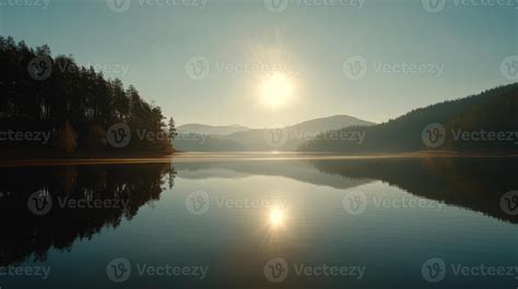 Serene morning sunrise over calm lake reflecting mountains and trees in ...
