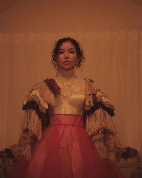 A Woman Standing In Front Of A Curtain Wearing A Red Skirt And White