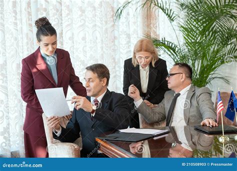 Two Delegates In Formalwear Consulting With Secretaries While Reading