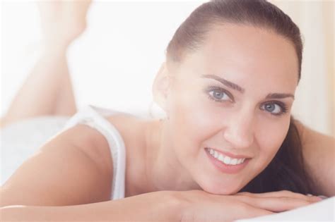 Premium Photo Smiling Brunette Lying On Bed Looking At Camera