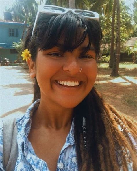 A Woman With Dreadlocks And A Flower In Her Hair Smiles At The Camera