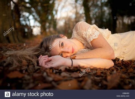 A Slim Blonde Woman Girl Alone Lying Down On The Ground In Woodland