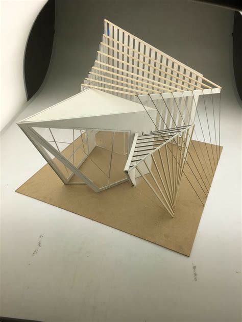 A Model Of A Building Made Out Of Wood And White Paper On Top Of A