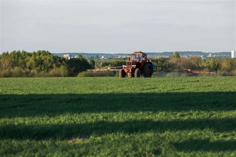 Agricultor no trator cultiva um fertilizante de plantação de campo