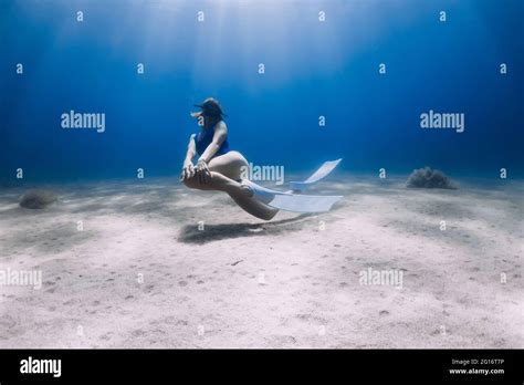 Lady Freediver With Fins Posing And Glides Underwater In Blue Ocean