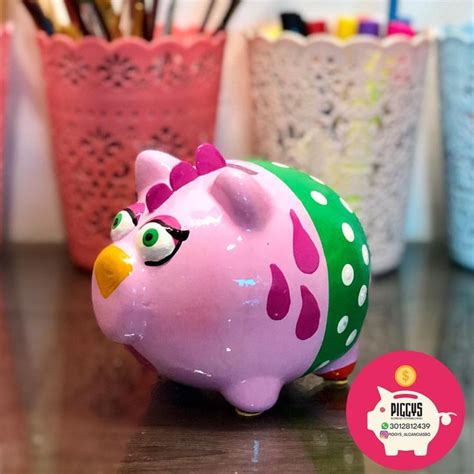 A Pink Piggy Bank Sitting On Top Of A Table Next To Pens And Pencils