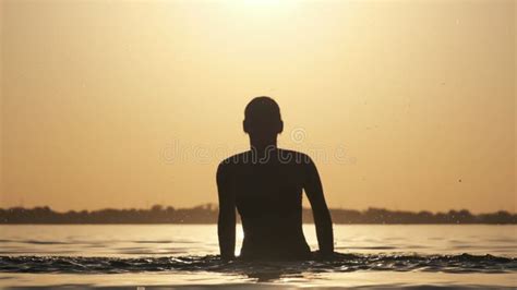 Silhouette Of Young Playful Cheerful Woman Splashing River Water At