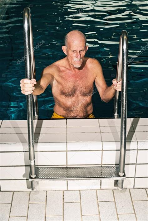 Senior man walking out of swimming pool. Wearing yellow swimming ...