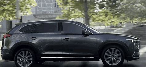 the new mazda cx - 9 is driving down the street in front of stairs