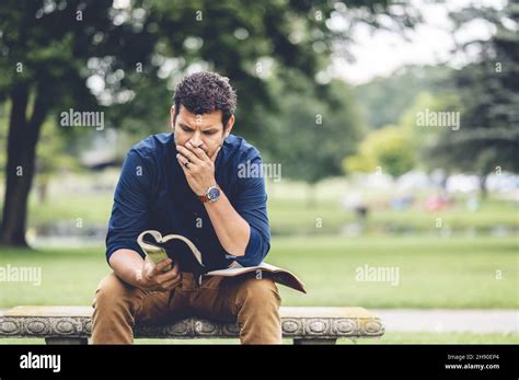 Caucasian Male Sitting In The Park And Reading The Holy Bible Stock