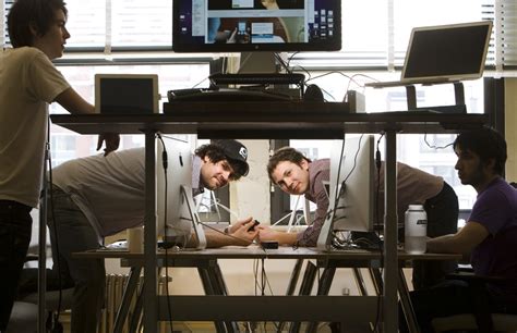 Three Men Sitting At A Table Looking At Something On The Computer