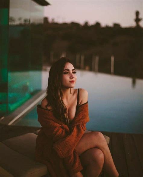 A Woman Sitting On Top Of A Wooden Deck Next To A Pool At Night Time