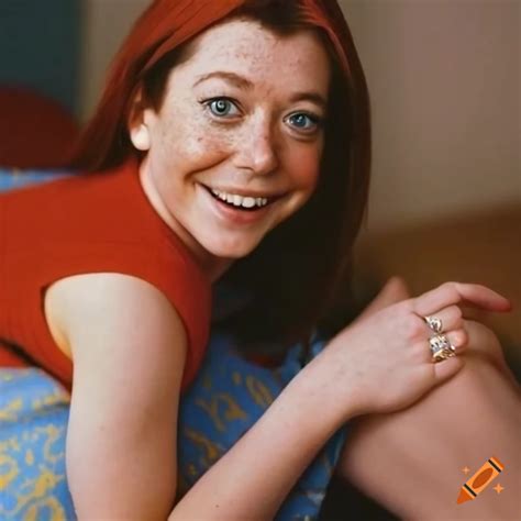 Alyson Hannigan Sitting On A Bed In A Hotel Wearing A Striped Sweater