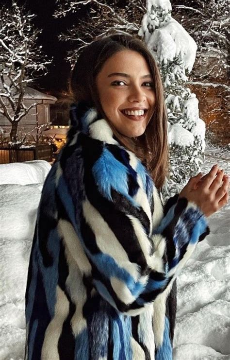 A Woman Is Standing In The Snow Wearing A Blue And Black Coat With