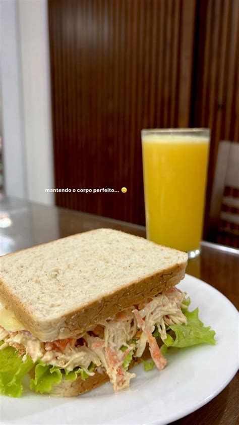 A White Plate Topped With A Cut In Half Sandwich Next To A Glass Of