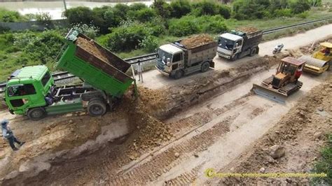 Dump Trucks Unloading Soil Building Road With Dozer Grading Excavator