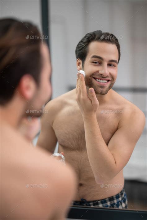 Half Naked Man Standing Near At The Mirror And Applying Shaving Foam On