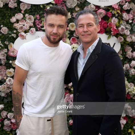 Two Men Standing Next To Each Other In Front Of A Floral Wall With