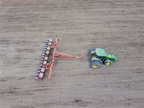 Premium Photo Sowing Of Corn Tractor With A Seeder On The Field Using