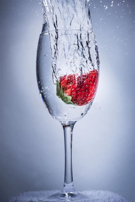 Zambullida Del Chapoteo De La Fresa En El Agua En Una Copa De Vino Foto