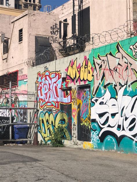 Graffiti On The Side Of A Building In An Alleyway With Fenced In Area