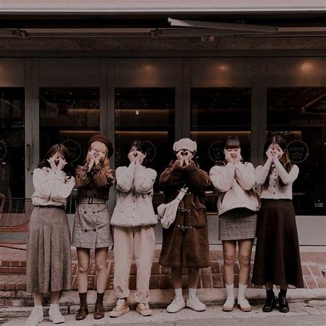 Four Girls Are Standing In Front Of A Store With Their Hands Up To