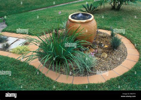 CIRCULAR PEBBLE GARDEN, TERRACOTTA TILE EDGING, CONTAINER FOUNTAIN, SISYRINCHIUM, TULBAGHIA ...