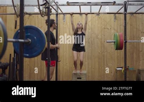 Personal Trainer Assisting Woman Doing Abdominal Pull Up Exercises