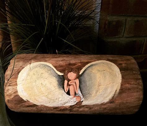 A Wooden Log With An Angel Painted On It And Plants In The Backround