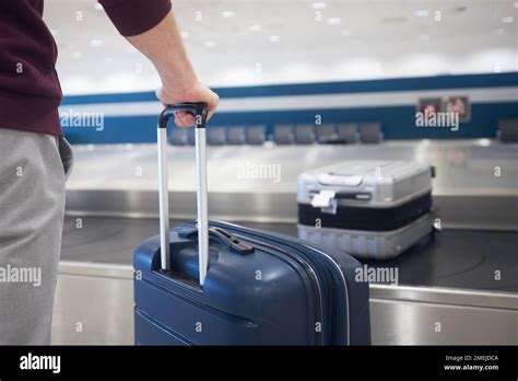 Traveling By Airplane Passenger Holding His Suitcase In Baggage Claim