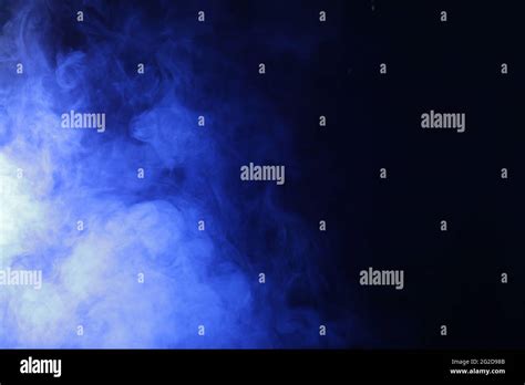 Magic smoke in blue light on black background Stock Photo - Alamy