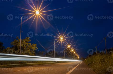 Low Angle View Of The Car Lights And Starlight From Roadside Lamp Posts