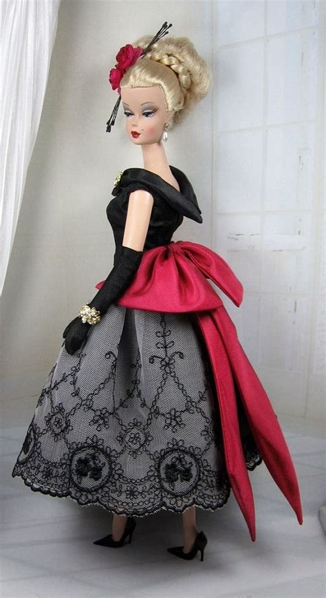 A Doll Wearing A Black And Red Dress With Flowers In Her Hair Is Standing On A White Surface