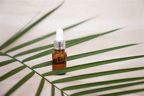 Blank Amber Glass Essential Oil Bottle With Pipette On Tropical Leaf