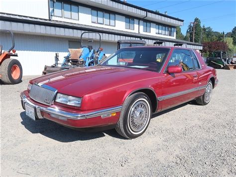 A Red Car Is Parked In Front Of A Building With Other Cars And