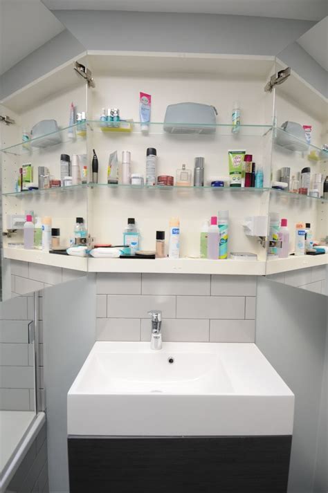 A White Sink Sitting Under A Bathroom Mirror Next To A Shelf Filled