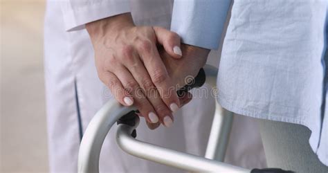 Female Nurse Holding Old Patient Hand Using Walking Frame Closeup