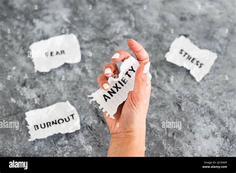 Hand Holding Anxiety Text On Scrunched Up Piece Of Paper Surrounded By