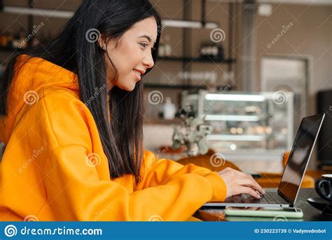 Smiling Asian Woman Working With Laptop While Sitting Stock Image