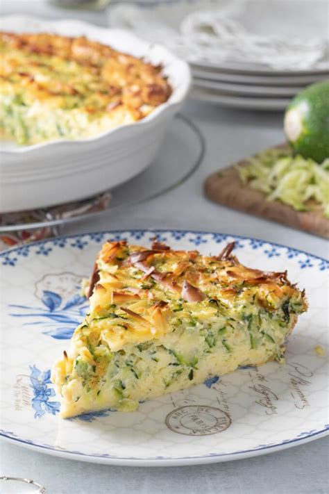 A Slice Of Quiche On A Blue And White Plate With Other Dishes In The Background