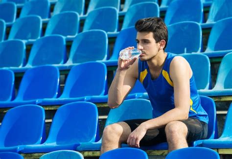 Hombre Bebiendo Agua De Una Botella En Una Tribuna Deportiva Foto Premium