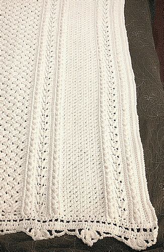 A White Crocheted Blanket Sitting On Top Of A Couch Next To A Pillow